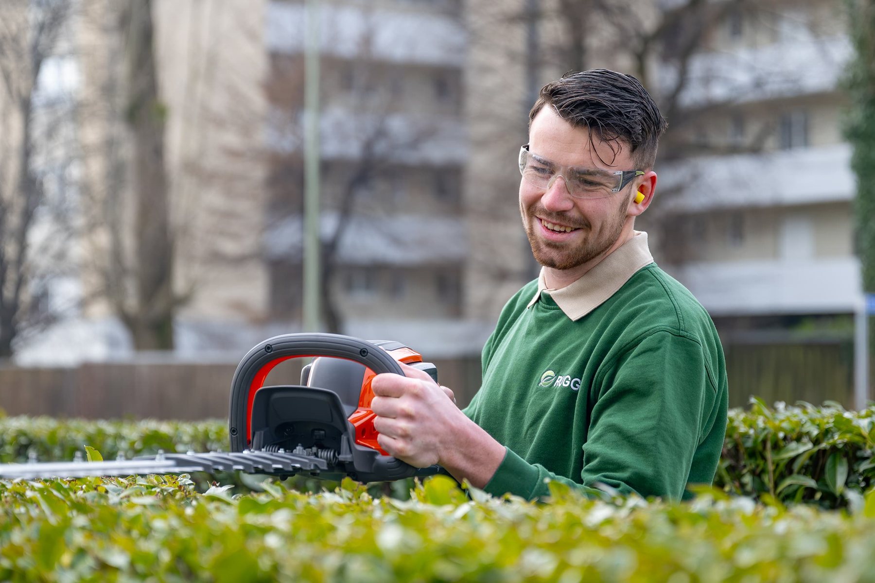 Gärtner mit Heckenschere vor einer Hecke